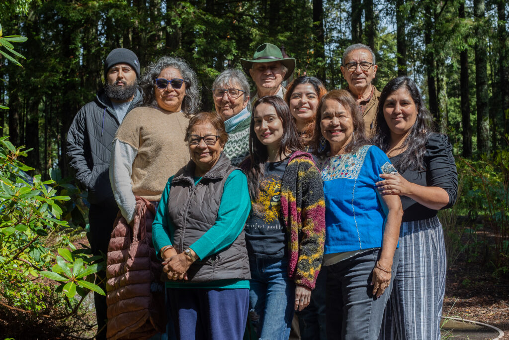 In two rows, a mixed-age group of ten people pose for a photo in a wooded area. 