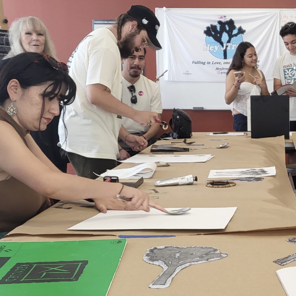 In the background is a banner that says 'hey JTree'. In the foreground are people gathered around a table, crafting and making art.